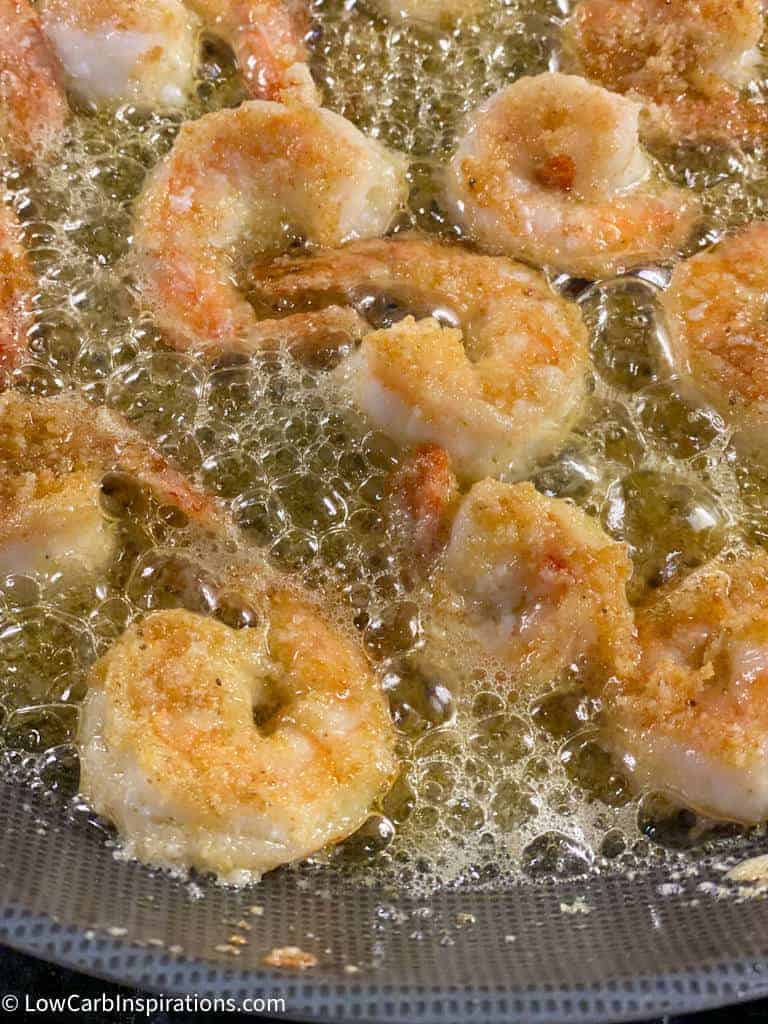 close up of shrimp cooking in oil on a gas stove