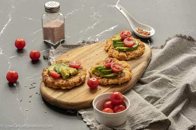 far away photo of savory pancakes on a wood cutting board topped with avocado and tomatoes