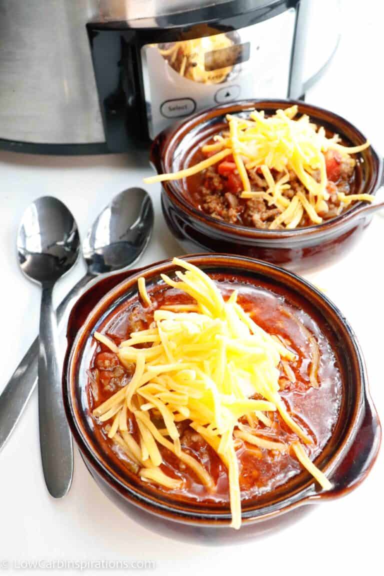 overhead shot of chili topped with cheese in a bowl in front of the crockpot